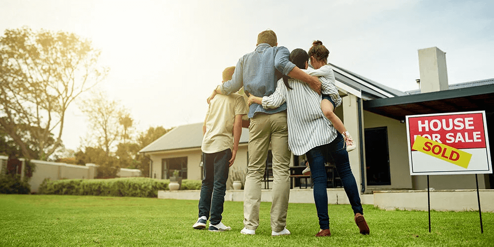 Family in front of their new home with a sold sign